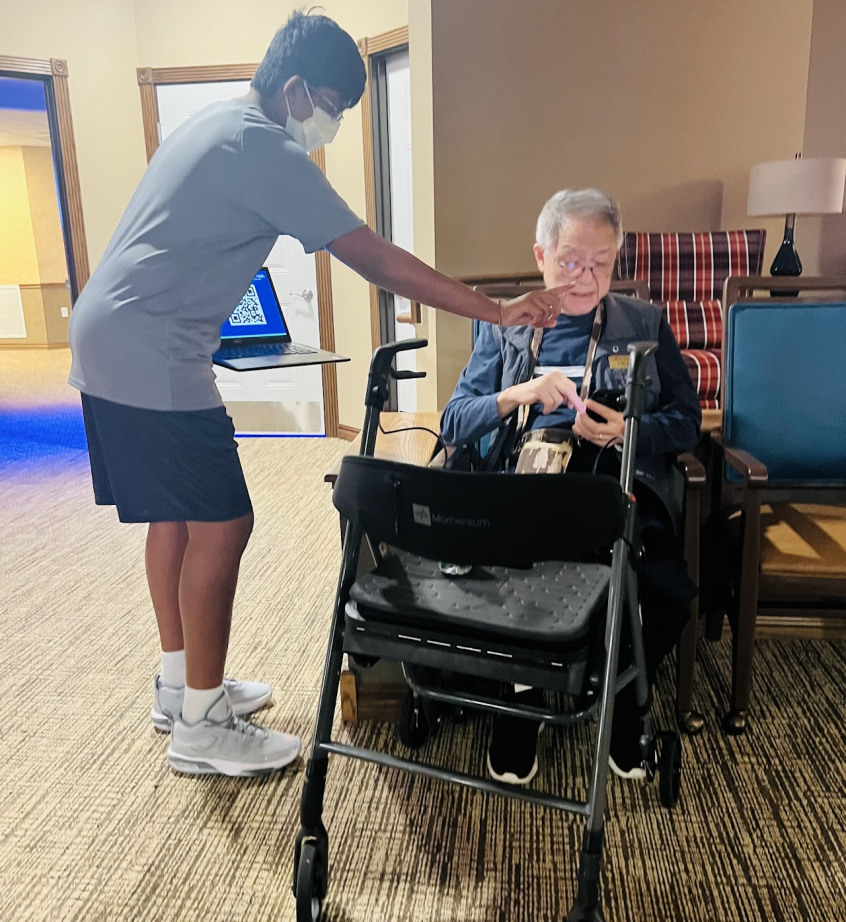 A student helping a senior at a senior living community
